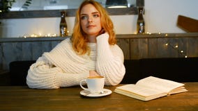 A mulher bonita nova está lendo um livro no café É de sorriso e de apreciação o aroma do café filme A mulher bonita nova está lendo um livro no café É de sorriso e de apreciação o aroma do café filme