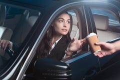 Mulher bonita nova no terno que senta-se no banco do condutor do carro e que recebe o café de imagens de stock Mulher bonita nova no terno que senta-se no banco do condutor do carro e que recebe o café de imagens de stock