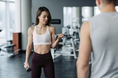 Mulher bonita nova que faz exerc?cios com peso no gym A menina de sorriso contente est? apreciando com seu processo do treinament imagem de stock Mulher bonita nova que faz exerc?cios com peso no gym A menina de sorriso contente est? apreciando com seu processo do treinament imagem de stock