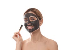 Mulher bonita que aplica a m?scara preta na cara imagem de stock Mulher bonita que aplica a m?scara preta na cara imagem de stock