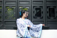 Mulher chinesa asiática no vestido azul e branco tradicional de Hanfu, jogo em um jardim famoso perto das janelas foto de stock royalty free Mulher chinesa asiática no vestido azul e branco tradicional de Hanfu, jogo em um jardim famoso perto das janelas foto de stock royalty free