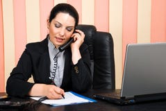 A mulher de negócio que fala pelo telefone e escreve no papel imagem de stock royalty free A mulher de negócio que fala pelo telefone e escreve no papel imagem de stock royalty free