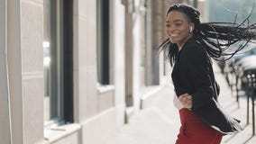 Mulher de negócios afro-americano feliz nova nos fones de ouvido que anda a rua da cidade ao escutar a música no video estoque Mulher de negócios afro-americano feliz nova nos fones de ouvido que anda a rua da cidade ao escutar a música no video estoque