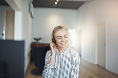 Mulher de negócios nova que ri ao falar em uns auriculares no trabalho imagem de stock royalty free Mulher de negócios nova que ri ao falar em uns auriculares no trabalho imagem de stock royalty free