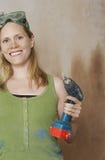 Mulher de sorriso com broca de poder da terra arrendada dos óculos de proteção protetores foto de stock Mulher de sorriso com broca de poder da terra arrendada dos óculos de proteção protetores foto de stock