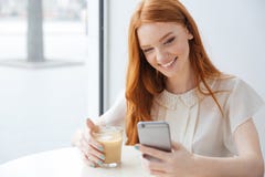 Mulher de sorriso que senta-se no café e em usar o telefone celular Foto de Stock Mulher de sorriso que senta-se no café e em usar o telefone celular Foto de Stock