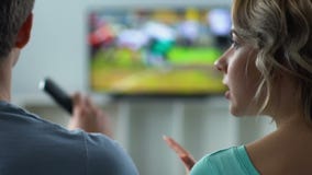 Mulher desagradada que discute com o futebol de observação na tevê, conflito do marido video estoque Mulher desagradada que discute com o futebol de observação na tevê, conflito do marido video estoque
