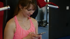 Mulher desportiva feliz que escreve uma mensagem em seu telefone celular no gym filme Mulher desportiva feliz que escreve uma mensagem em seu telefone celular no gym filme