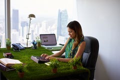 A mulher do ecologista datilografa o email com a tabuleta na mesa de escritório imagem de stock A mulher do ecologista datilografa o email com a tabuleta na mesa de escritório imagem de stock