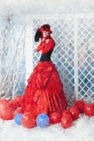 A mulher em um vestido antigo vermelho está congelando-se sob a neve de queda imagens de stock A mulher em um vestido antigo vermelho está congelando-se sob a neve de queda imagens de stock
