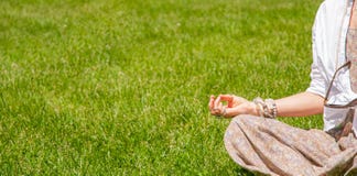 A mulher est? meditando o assento na pose de Lotus na grama no parque Estilo de Boho com acess?rios, an?is e braceletes imagens de stock royalty free A mulher est? meditando o assento na pose de Lotus na grama no parque Estilo de Boho com acess?rios, an?is e braceletes imagens de stock royalty free