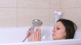 A mulher está tomando um banho Relaxe após um dia mau Toque em uma água com mão A mulher está tomando um banho Relaxe após um dia mau Toque em uma água com mão