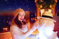Mulher feliz bonita que faz o boneco de neve sob a neve mágica do inverno foto de stock royalty free Mulher feliz bonita que faz o boneco de neve sob a neve mágica do inverno foto de stock royalty free