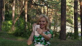 Mulher feliz que acena no bate-papo video com o smartphone na floresta exterior vídeos de arquivo Mulher feliz que acena no bate-papo video com o smartphone na floresta exterior vídeos de arquivo