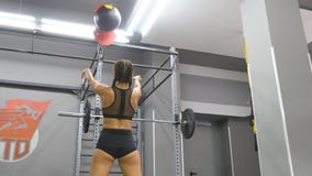 Mulher forte nova com o corpo perfeito da aptidão no sportswear que exercita com a bola de medicina no gym Menina que faz o cross imagem de stock Mulher forte nova com o corpo perfeito da aptidão no sportswear que exercita com a bola de medicina no gym Menina que faz o cross imagem de stock