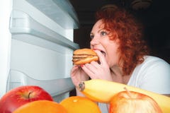 A mulher grande come o fast food Menina gorda do cabelo vermelho que olha o refrig interno fotografia de stock A mulher grande come o fast food Menina gorda do cabelo vermelho que olha o refrig interno fotografia de stock
