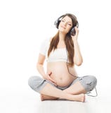Mulher gravida que escuta a música nos auscultadores e no ove de relaxamento fotografia de stock royalty free Mulher gravida que escuta a música nos auscultadores e no ove de relaxamento fotografia de stock royalty free