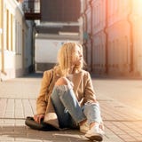 A mulher loura consideravelmente elegante dos jovens vestiu-se em calças de brim rasgadas fotografia de stock A mulher loura consideravelmente elegante dos jovens vestiu-se em calças de brim rasgadas fotografia de stock