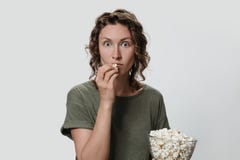 Mulher milenar nova com cabelo encaracolado que come a pipoca, olhando um filme ou programas televisivo fotografia de stock Mulher milenar nova com cabelo encaracolado que come a pipoca, olhando um filme ou programas televisivo fotografia de stock