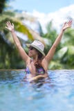 A mulher moreno magro nova toma sol na piscina tropical imagem de stock A mulher moreno magro nova toma sol na piscina tropical imagem de stock