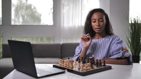 Mulher jogando xadrez online no laptop na mesa fechada