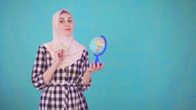 Mulher muçulmana bonita nova com o modelo do globo que olha o sorriso da câmera video estoque Mulher muçulmana bonita nova com o modelo do globo que olha o sorriso da câmera video estoque