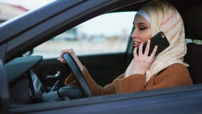 Mulher muçulmana moderna que tem uma conversa do telefone na roda Mulher muçulmana moderna que tem uma conversa do telefone na roda