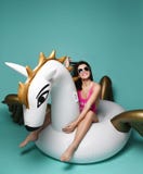 Mulher nova da forma que relaxa com o colchão inflável grande do flutuador de pegasus do unicórnio no biquini cor-de-rosa 'sexy' imagens de stock Mulher nova da forma que relaxa com o colchão inflável grande do flutuador de pegasus do unicórnio no biquini cor-de-rosa 'sexy' imagens de stock