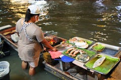 A mulher que está na água está cozinhando o marisco para turistas no mercado de flutuação Banguecoque, Tailândia Fotos de Stock Royalty Free A mulher que está na água está cozinhando o marisco para turistas no mercado de flutuação Banguecoque, Tailândia Fotos de Stock Royalty Free