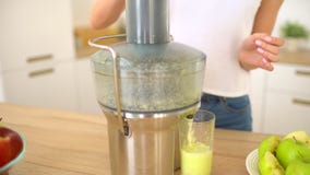 Mulher que faz o suco de maçã no juicer e que bebe o fresco em casa na cozinha Juicing e mulher feliz comendo saudável video estoque Mulher que faz o suco de maçã no juicer e que bebe o fresco em casa na cozinha Juicing e mulher feliz comendo saudável video estoque