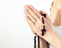 Mulher que guarda uma cruz com grânulos e rezar do rosário fotografia de stock Mulher que guarda uma cruz com grânulos e rezar do rosário fotografia de stock