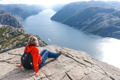 Mulher que senta-se na rocha do púlpito/Preikestolen, Noruega fotos de stock royalty free Mulher que senta-se na rocha do púlpito/Preikestolen, Noruega fotos de stock royalty free