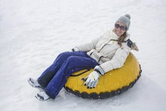 Mulher que sledding abaixo de um monte em um tubo da neve fotografia de stock royalty free Mulher que sledding abaixo de um monte em um tubo da neve fotografia de stock royalty free