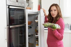 Mulher que verifica a venda na data no saco da salada no refrigerador fotografia de stock royalty free Mulher que verifica a venda na data no saco da salada no refrigerador fotografia de stock royalty free