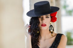 Mulher que veste o chapéu espanhol e cravos vermelhos em seu cabelo fotografia de stock Mulher que veste o chapéu espanhol e cravos vermelhos em seu cabelo fotografia de stock