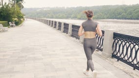 Mulher running na terraplenagem da cidade durante a formação da manhã exterior vídeos de arquivo Mulher running na terraplenagem da cidade durante a formação da manhã exterior vídeos de arquivo