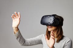 A mulher senta-se em auriculares da realidade de Sofa At Home Wearing Virtual