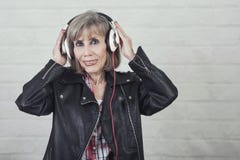 Mulher superior de sorriso com fones de ouvido que escuta a música fotografia de stock royalty free Mulher superior de sorriso com fones de ouvido que escuta a música fotografia de stock royalty free