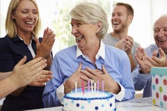 A mulher superior funde para fora velas do bolo de aniversário no partido da família imagem de stock A mulher superior funde para fora velas do bolo de aniversário no partido da família imagem de stock
