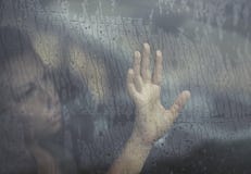 Mulher triste que olha através da janela com gota da chuva no carro Cara da fêmea nova atrás da janela de carro da chuva imagem de stock royalty free Mulher triste que olha através da janela com gota da chuva no carro Cara da fêmea nova atrás da janela de carro da chuva imagem de stock royalty free