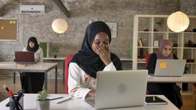 Mulheres muçulmanas pretas novas no hijab que trabalha no portátil e no bocejo, cansados, o assento de três mulheres muçulmanas b vídeos de arquivo Mulheres muçulmanas pretas novas no hijab que trabalha no portátil e no bocejo, cansados, o assento de três mulheres muçulmanas b vídeos de arquivo