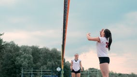 Mulheres que competem em um competiam profissional do voleibol de praia Um defensor tenta parar um tiro durante as 2 mulheres filme Mulheres que competem em um competiam profissional do voleibol de praia Um defensor tenta parar um tiro durante as 2 mulheres filme