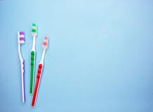 Multi-colored toothbrushes on a blue background with copy space stock images Multi-colored toothbrushes on a blue background with copy space stock images