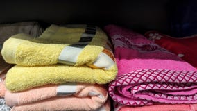 Multi-colored towels on a shelf in the market, sale of cotton towels, a stack of colored cotton towels front view