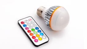 Multi colour LED light bulb and remote control royalty free stock photo Multi colour LED light bulb and remote control royalty free stock photo