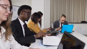 Multi-etnische groep jonge bedrijfsmensen die bij de lijst aangaande conferentie in de vergaderzaal zitten Een groep gemengd stock video Multi-etnische groep jonge bedrijfsmensen die bij de lijst aangaande conferentie in de vergaderzaal zitten Een groep gemengd stock video