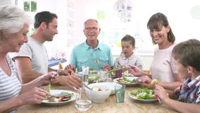 Multi Generation Family Eating Meal Around Kitchen Table