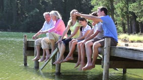 Multi-Generation Family Sitting On Wooden Jetty By Lake stock video Multi-Generation Family Sitting On Wooden Jetty By Lake stock video