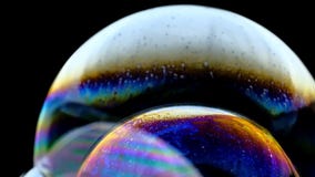 Multicolored rainbow colors of a single soap bubble that looks like a fantasy planet isolated against a black background