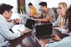 multiculturele partners die vergadering hebben bij lijst met laptops en glazen water in modern royalty-vrije stock afbeeldingen multiculturele partners die vergadering hebben bij lijst met laptops en glazen water in modern royalty-vrije stock afbeeldingen